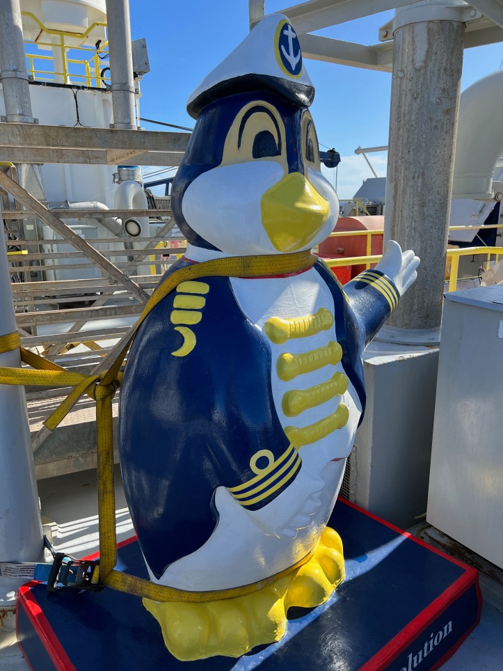 penguin statue dressed like a sailor tied down on a ship